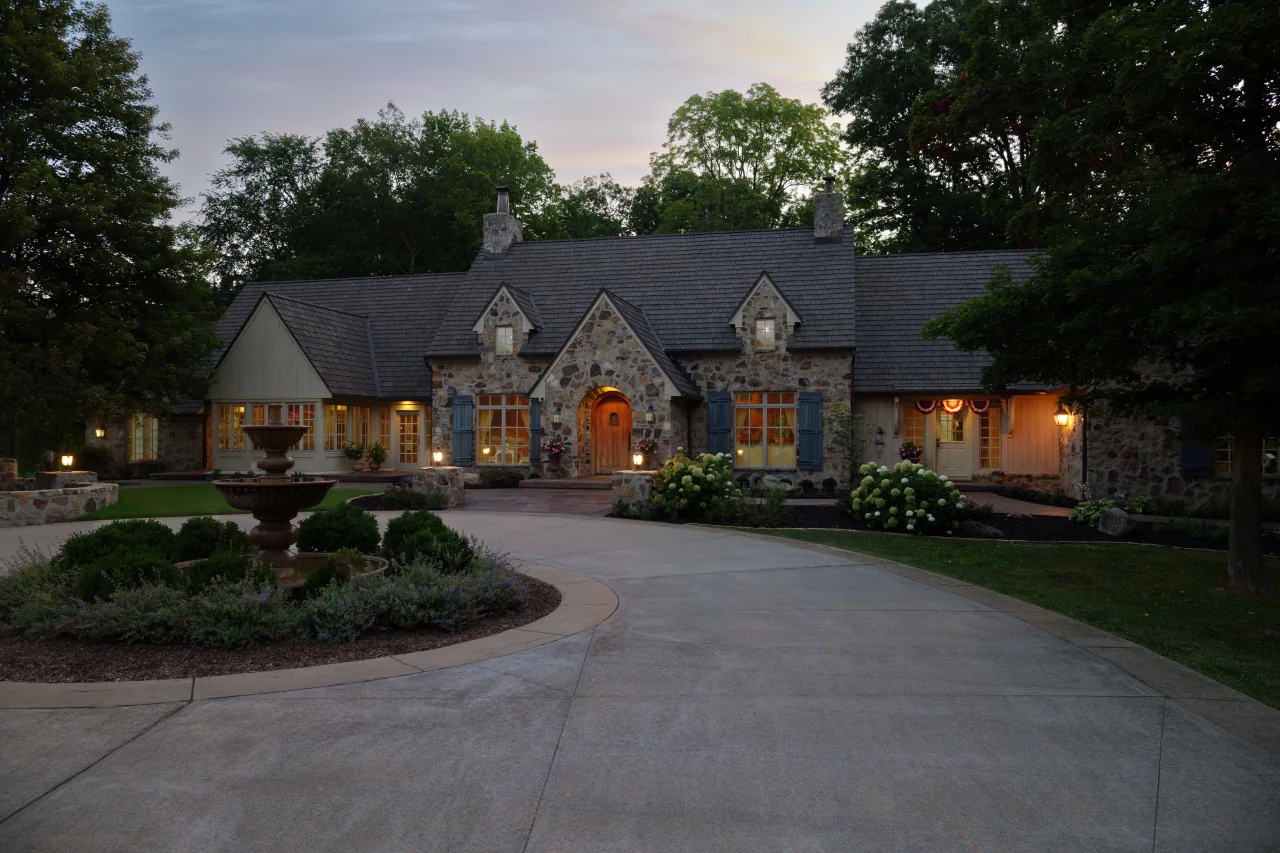 Zionsville residence with a Brava composite cedar roof and standing-seam pool house at twilight
