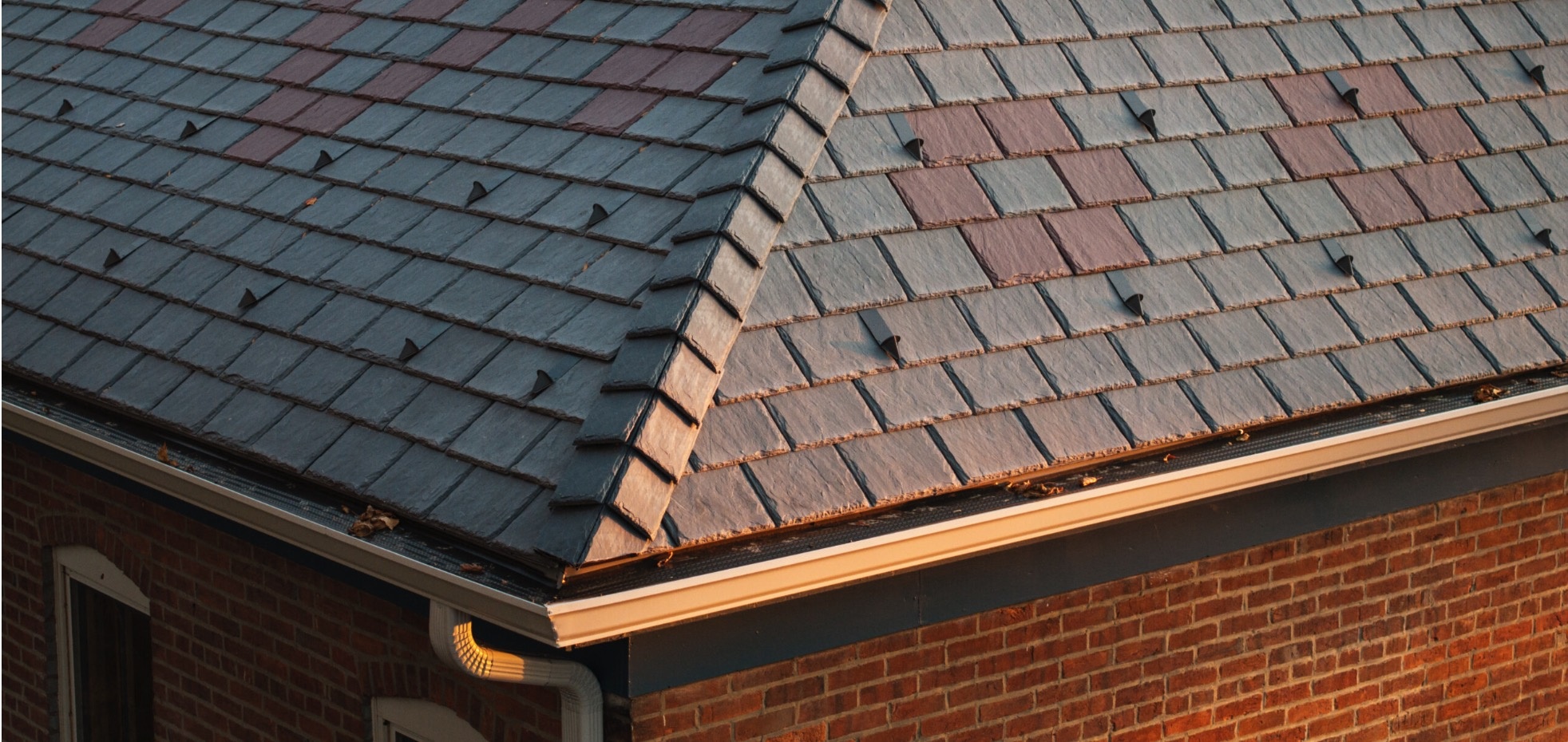 Continuous gutter-guard panels installed along intersecting eaves on a slate-profile roof