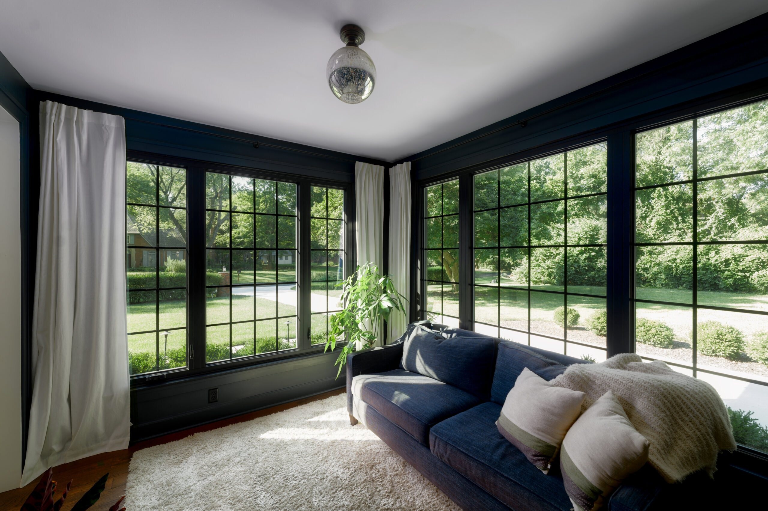 Broad corner window arrangement creating an expanded view from a living room