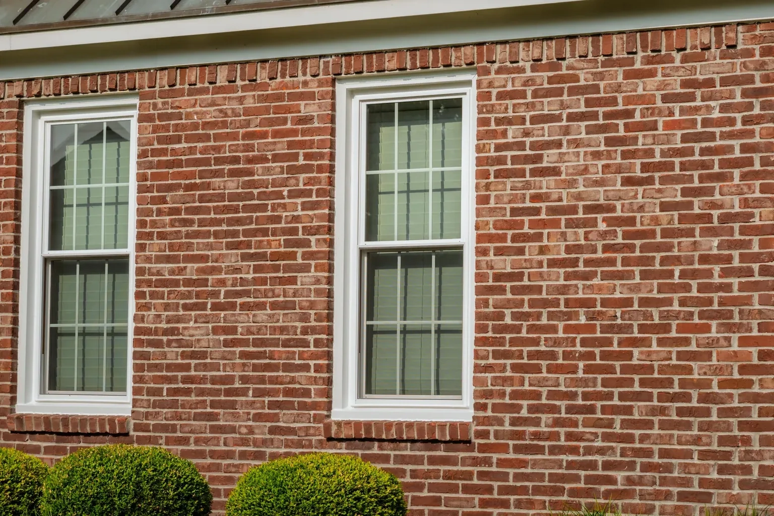 Close exterior view of two white double-hung windows with upper and lower sashes