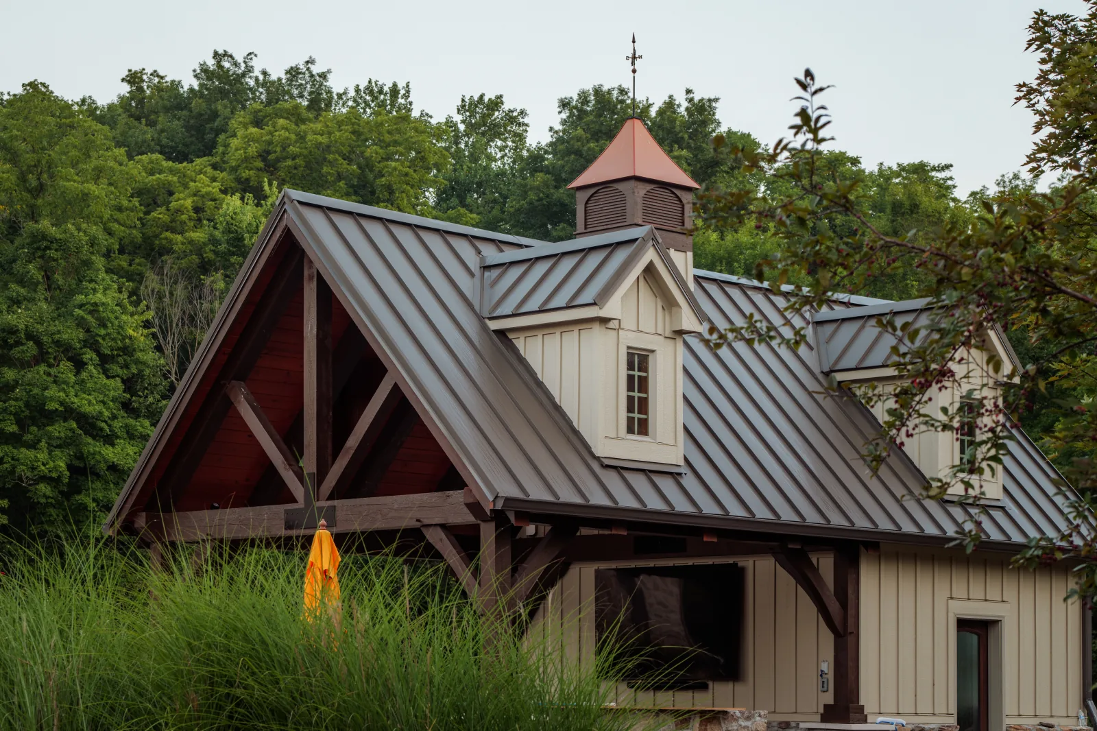 Pool house with a deep-bronze standing-seam metal roof