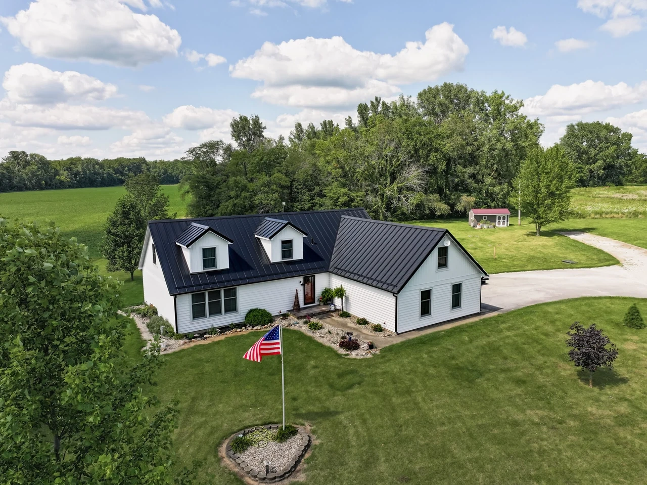 Modern farmhouse with a black metal roof, aerial view