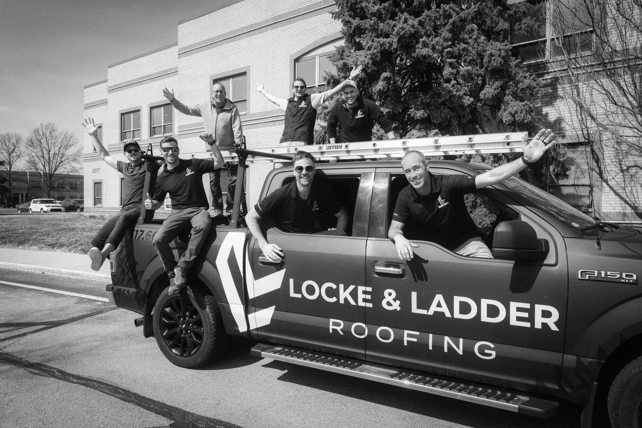 The Locke & Ladder roofing crew gathered on and around a branded company truck, smiling